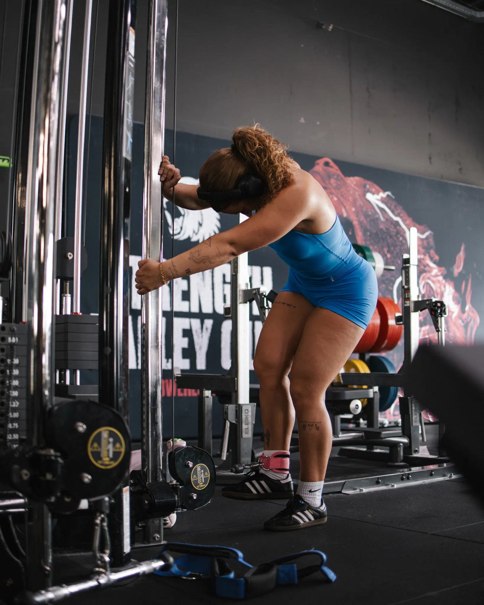 Lifter hangt in de kabelmachine met het opschrift Strength Valley op de wand achter haar